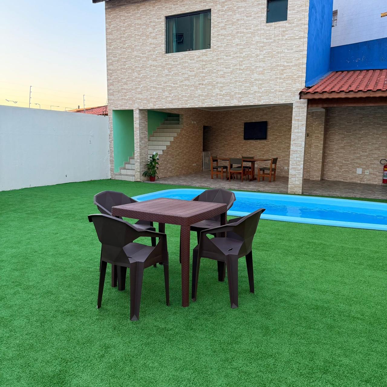 Jardim gramado com mesa e piscina para dias de sol